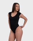 Woman wearing a black bodysuit on a white background