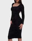A model wearing a black ruched long sleeve midi dress with a square neckline.