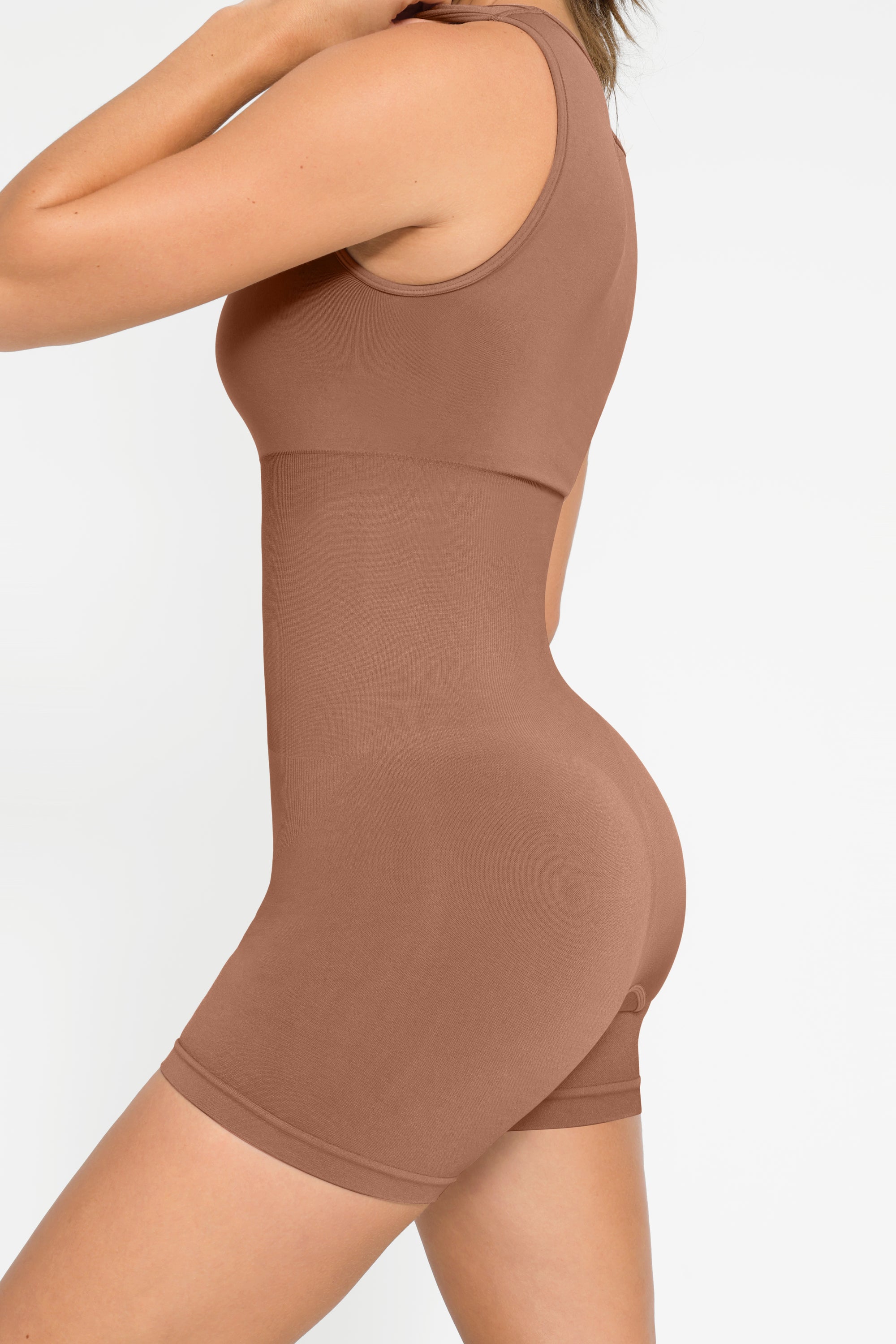 A person wearing a brown square neck short jumpsuit.