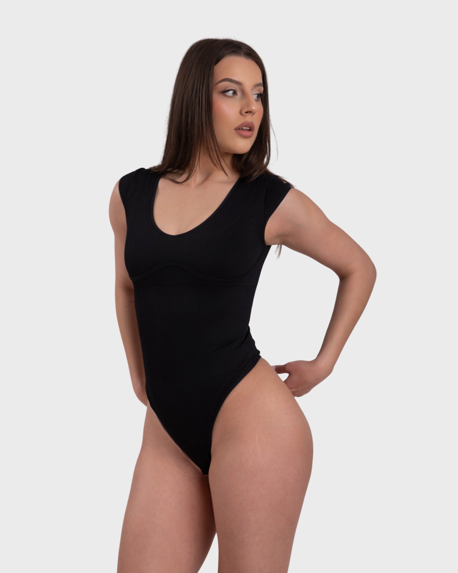 Woman wearing a black bodysuit on a white background