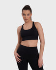 A woman wearing a black sports bra and matching leggings.