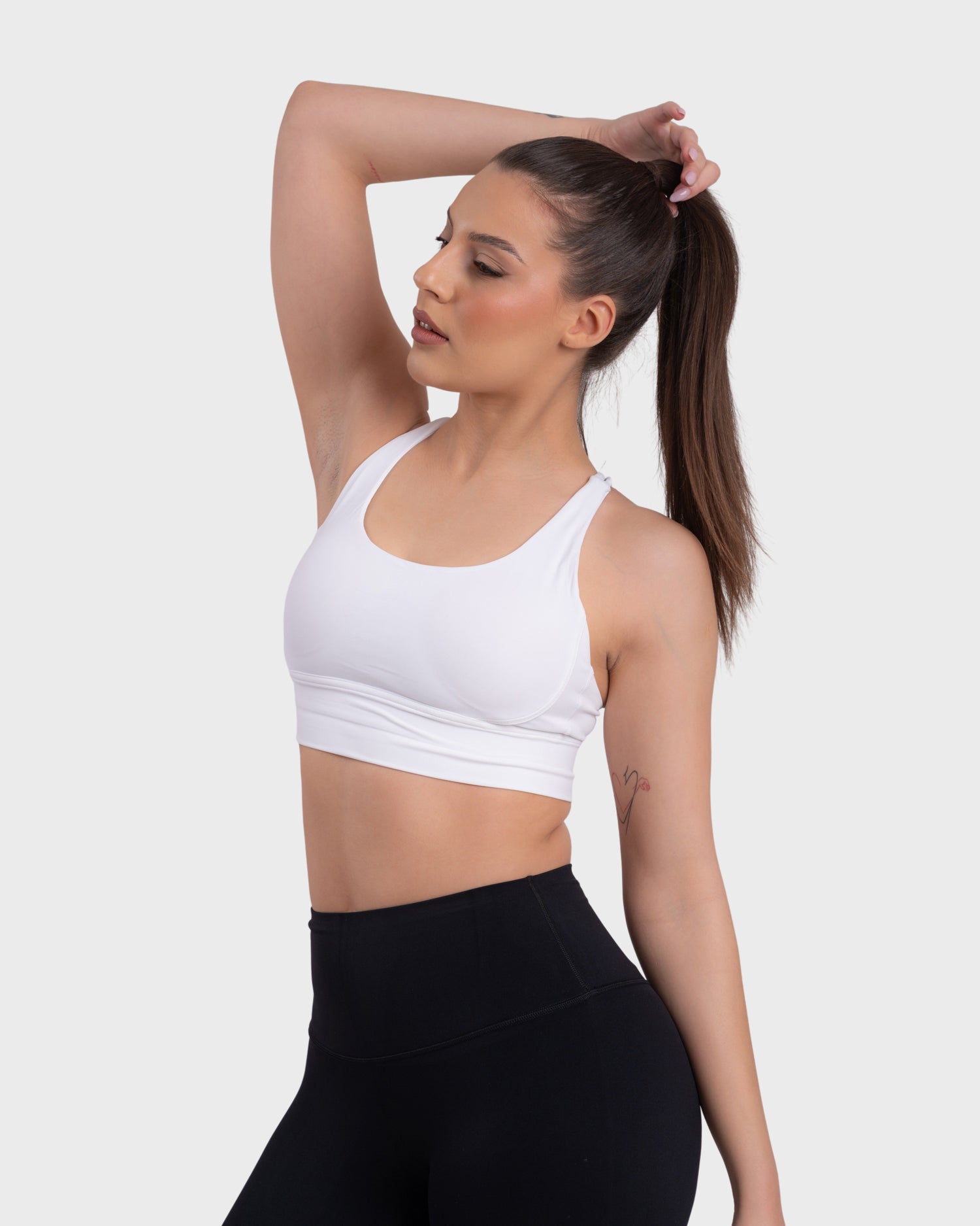 A woman wearing a white sports bra and black Activewear leggings.